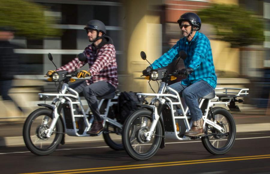 Ethan Ralston (left) and his father Bob Ralston ride the latest street-legal version of their Ubco electric motorcycle through downtown Eugene recently. 